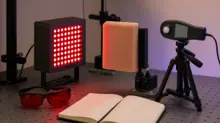 Rødt LED-panel målt med sensor foran en testblok på et neutralt laboratoriebord